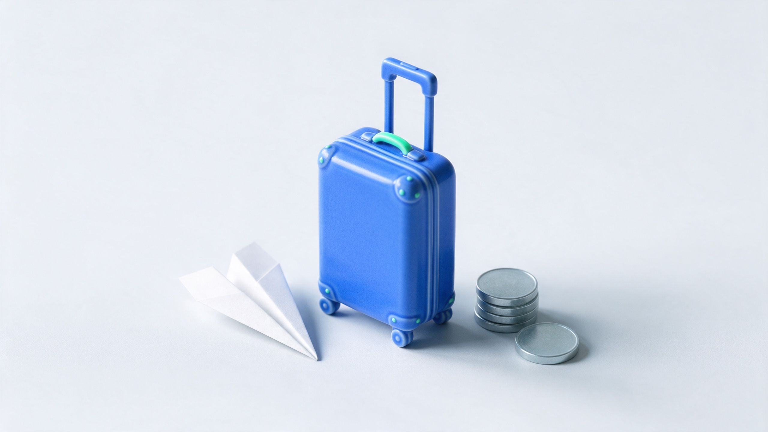 A small blue suitcase next to a paper plane and a stack of coins
