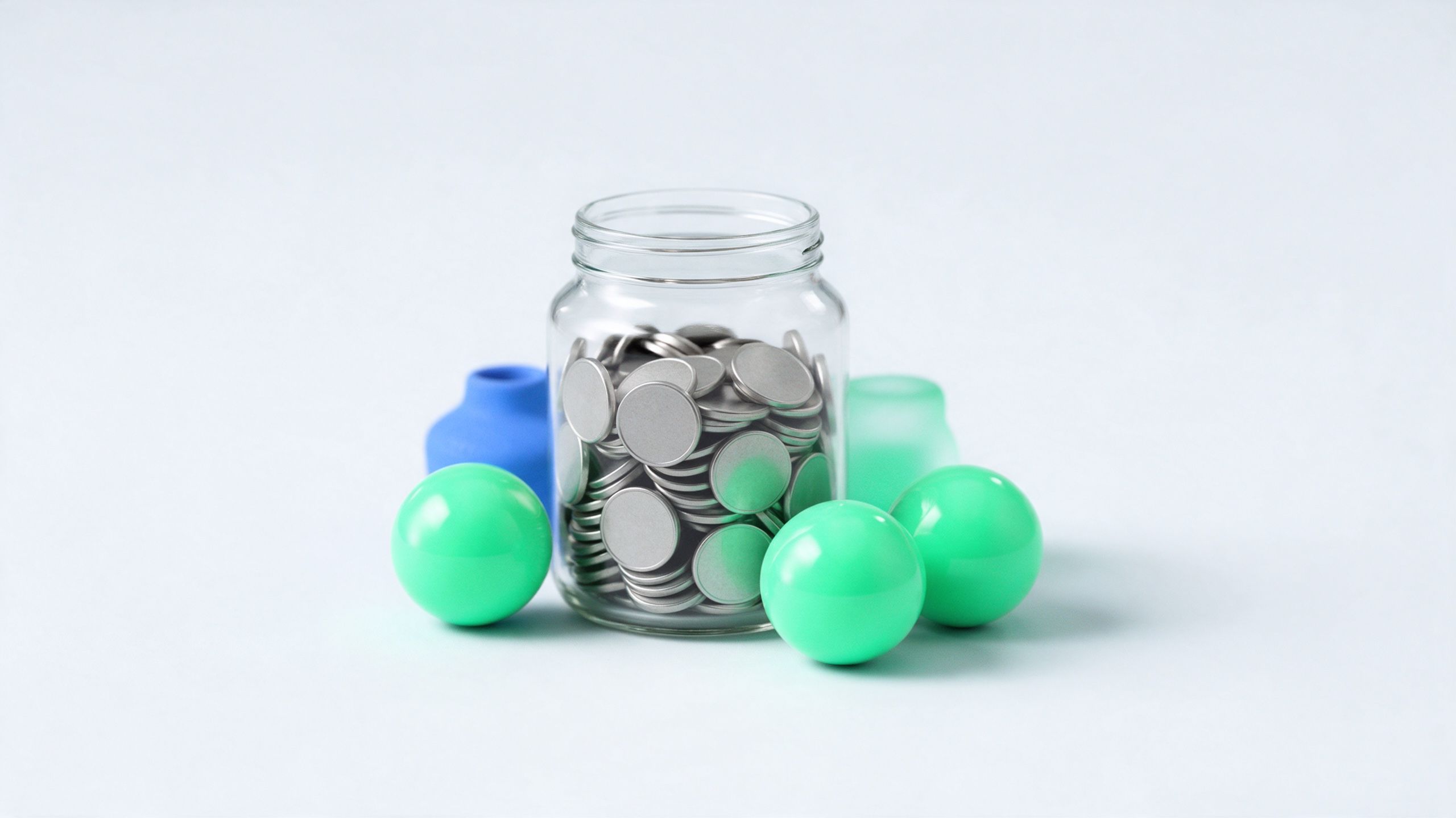 A glass jar of coins next to three green prize-draw balls